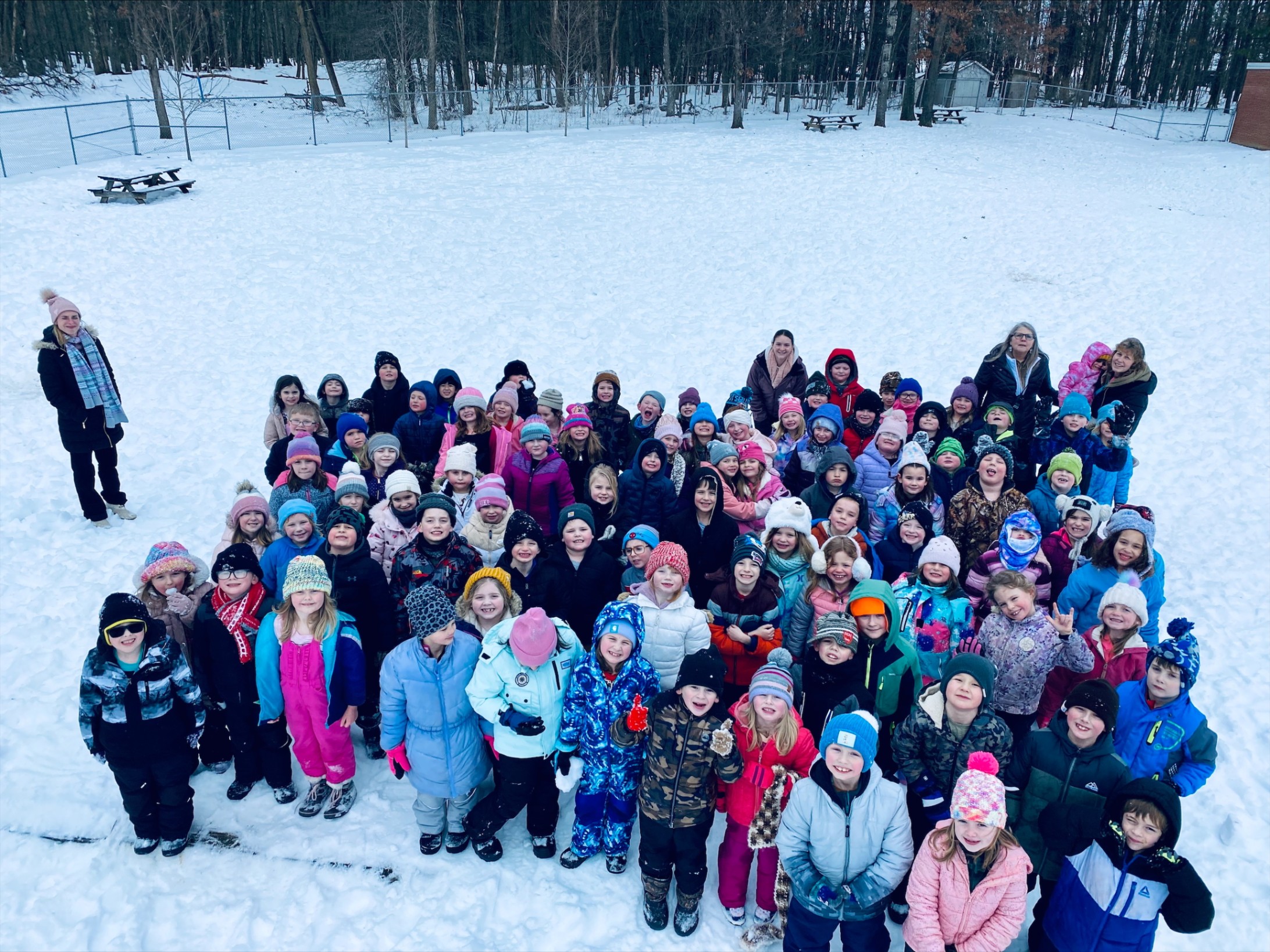 First graders and their teachers pose for a group photo outside in the snow.
